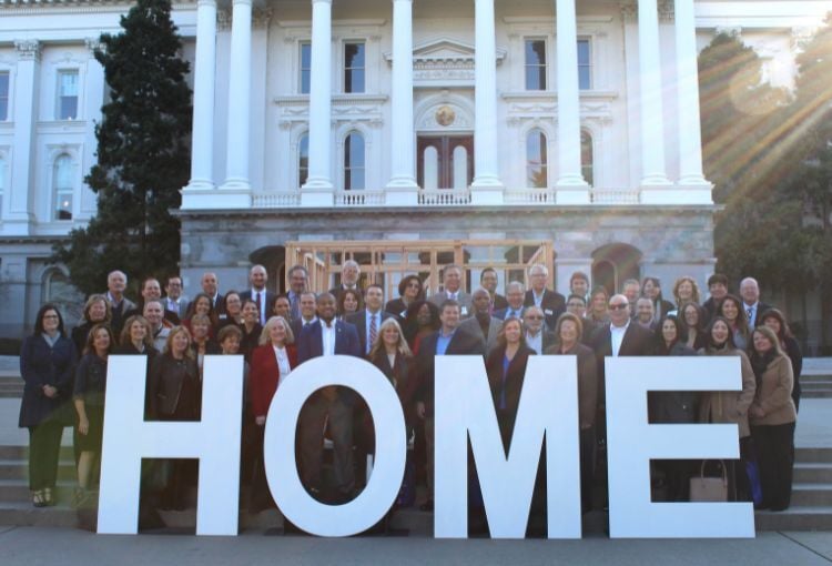 Habitat advocates standing on the steps of the CA state Capitol with a sign that reads HOME