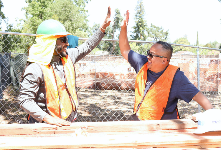 volunteers high-fiving on a construction site