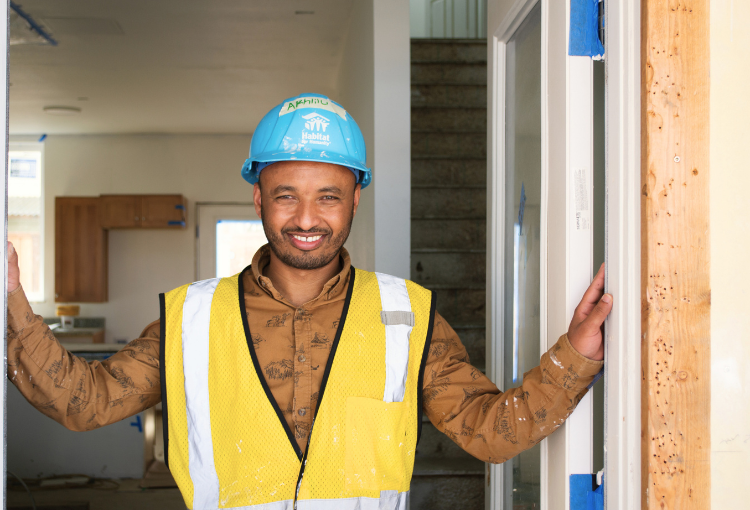 Future Habitat Homeowner, Akhlilu, stands in the doorway of a home under construction at Sequoia Grove 