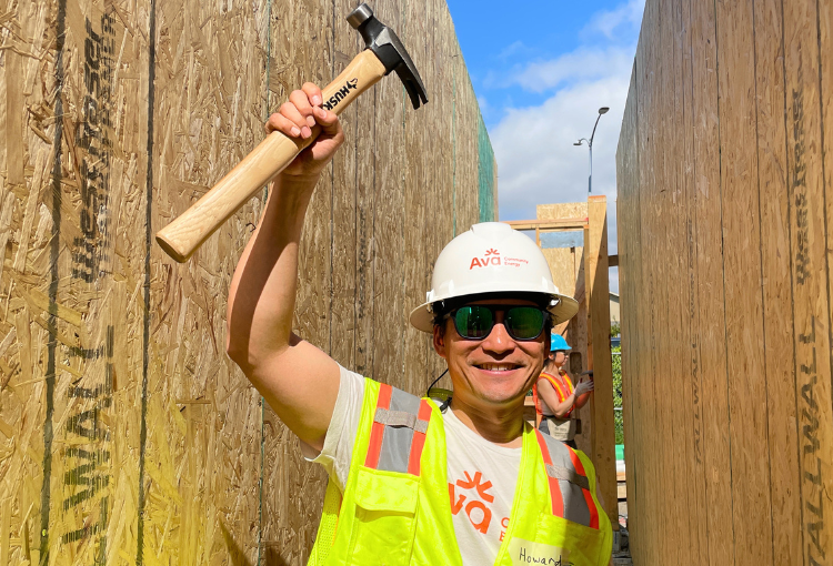 Howard Chang, CEO of Ava Community Energy, raises a hammer while volunteering at Sequoia Grove