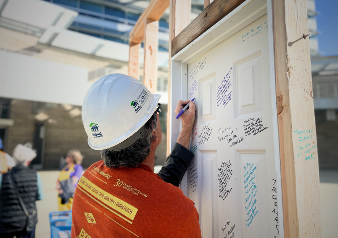 Habitat volunteer wearing a hardhat signing Habitat's memorial wall for President Carter