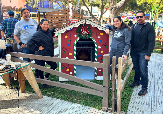 Volunteers from NetApp stand in front of the playhouse they built for the Christmas in the Park Playhouse Village competition.
