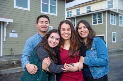 Silvia and her kids smiling in front of their new Habitat home. 