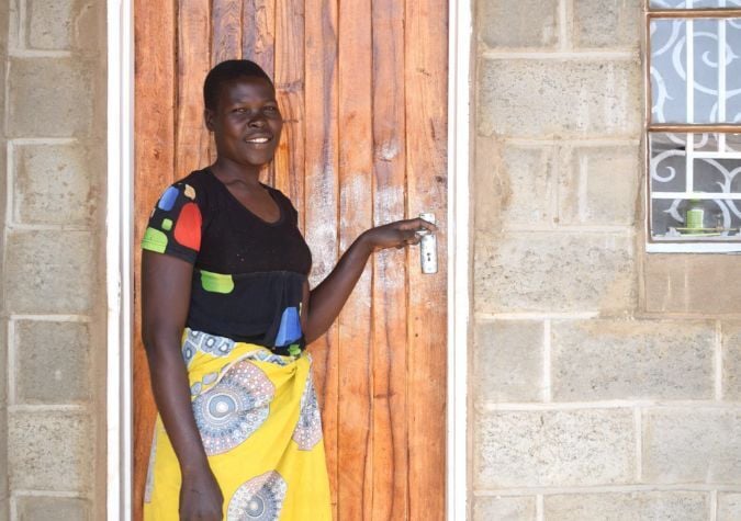 Image of a homeowner in front of her door in Malawi